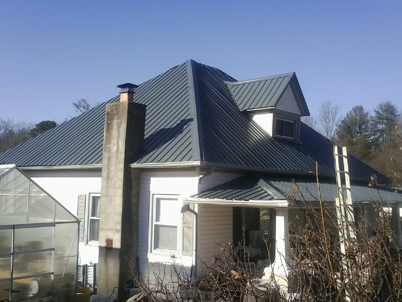 Dark blue standing seam metal roof on a white farmhouse with dormer — Slate & Tile Roof Repair by Roofing Brothers in Muncy