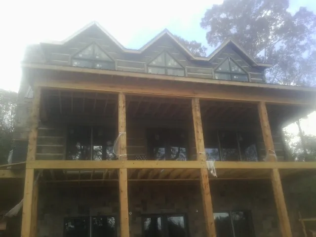 Dormers and porch framing on a large log home under construction — Roof Coating work by our crew in Muncy
