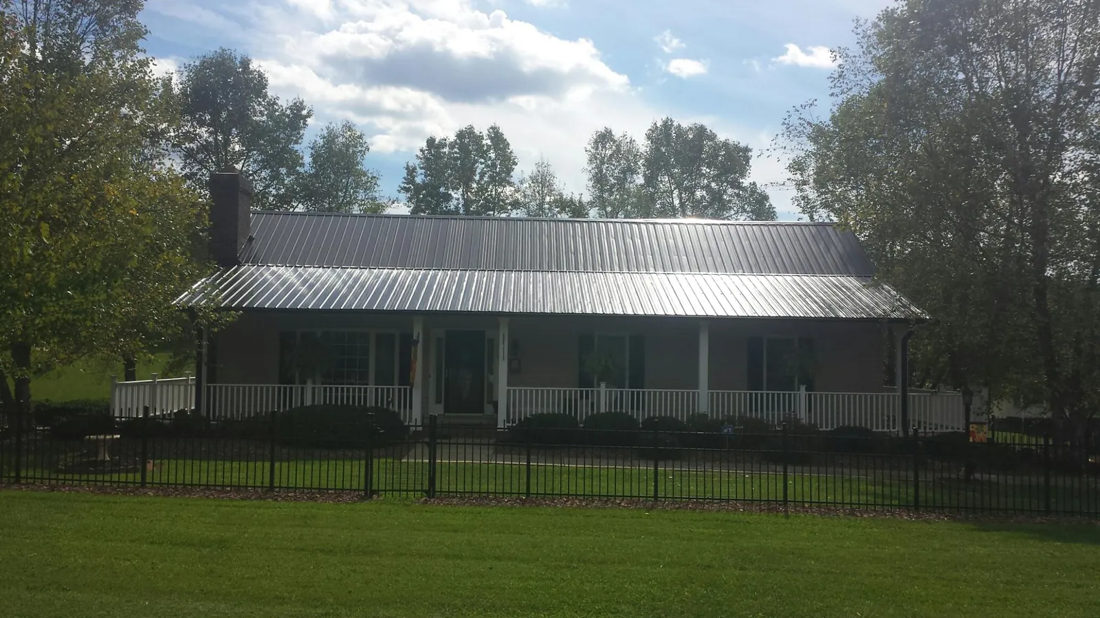 Gray metal roof on a brick ranch with a full width front porch — Gutter Guard Installation work by our crew in Muncy