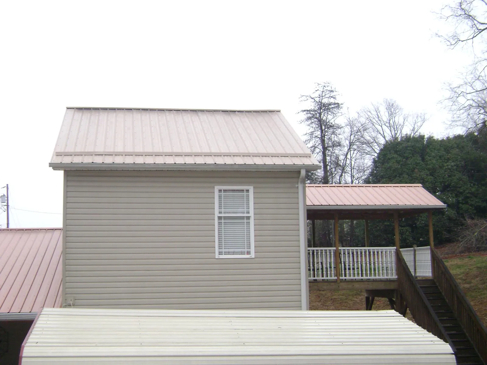 Tan metal roofs on a two story addition and attached porch, from a Roof Replacement job in Muncy