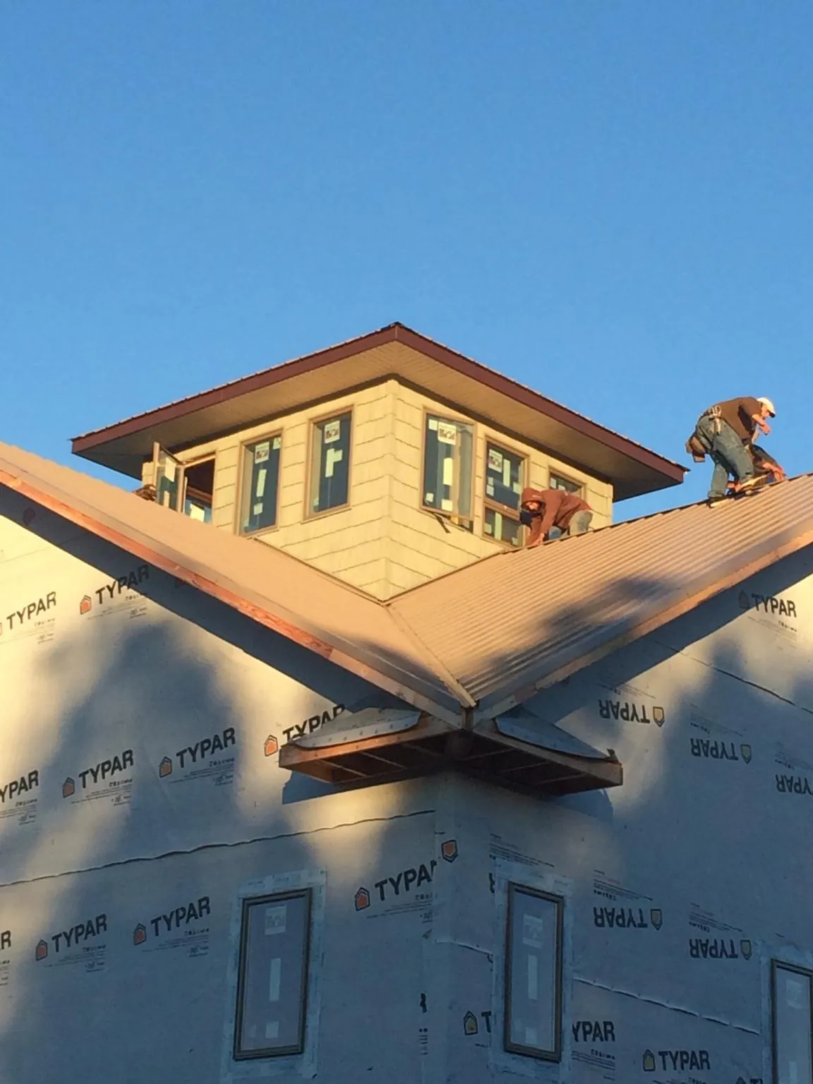 Roofers working around a rooftop cupola on a new metal roof at sunset — Roof Waterproofing in Muncy by Roofing Brothers
